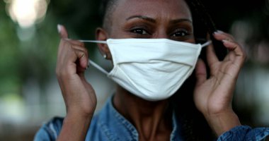 Siyahi kadın salgının sona ermesini kutlayan siyah maskesini çıkarıyor.