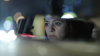 Woman driving at night seen through rear-view mirror