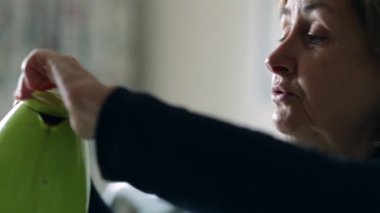 Açık yürekli, olgun bir kadın kahvaltı için kahve ve içki servisi yapıyor.