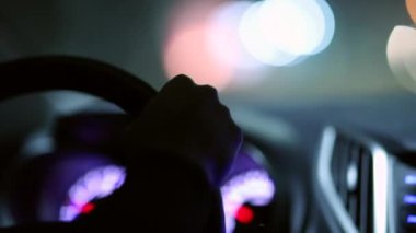 Hands holding steering wheel driving at night in slow-motion