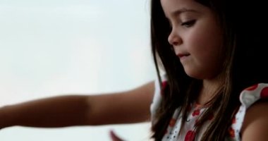 Little girl playing with slimy plasticine creating a bubble with blue slime