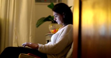 Geceleri evde çalışan dürüst bir kadın dizüstü bilgisayarın önünde daktilo yazarken.