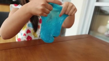 Küçük kız sümüklü lastik oyuncakla oynuyor. Mavi sümüklü çocuk