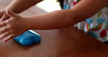 Yakın plan çocuk elleri mavi plastik yapışkanla oynuyor.