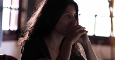 Hüsrana uğramış genç bir kadın evde oturmuş endişe ve endişe duyuyor.