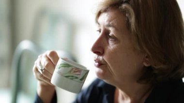 Sıradan bir kadın kahvaltı masasında bir yudum kahve içiyor.