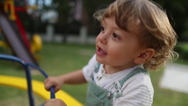 楽しい幼児の子供が遊び場で回転していますカルーセル 子供の現実の笑いと笑顔 — ストック動画
