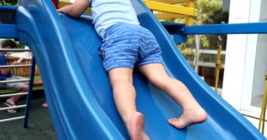 Bebek çocuk oyun parkından aşağı iniyor. Geriye doğru kayıyor.