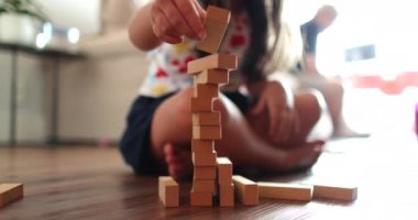 Little girl playing with building wooden blocks at home