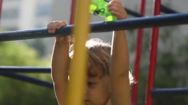 Bebek çocuk oyun parkında maymun barına sarılmış.