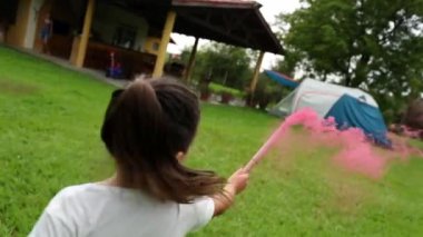 Kız havai fişeklerle oynuyor. Çocuk dışarıda kırmızı dumanla oynuyor.