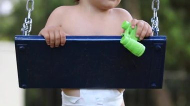 Çocuk parkta oynuyor. Dışarıda salıncakta sallanıyor.