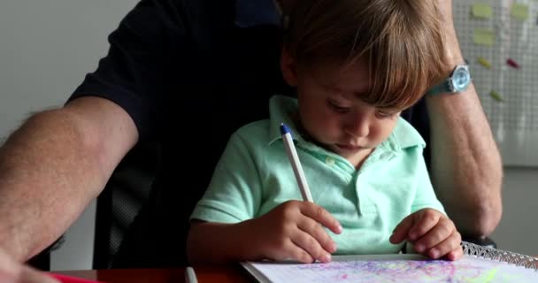 Ένα Μικρό Παιδί Ζωγραφίζει Χαρτί Ενώ Κάθεται Στην Αγκαλιά Του — Αρχείο Βίντεο