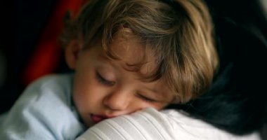 Küçük çocuk annesinin omzunda uyuyor. Çocuk uyuyor. Bebek uykusu.