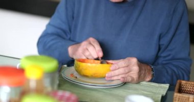 Yaşlı adam sabah kahvaltıda papaya meyvesi yiyor.