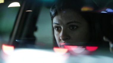 Woman driving at night seen through rear-view mirror