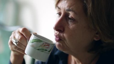 Sıcak kahve üfleyen sıradan yaşlı bir kadın.