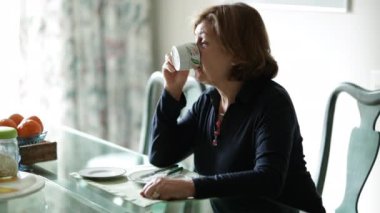 Sabahları kahvaltı masasında bir yudum kahve içen sıradan bir kadın.