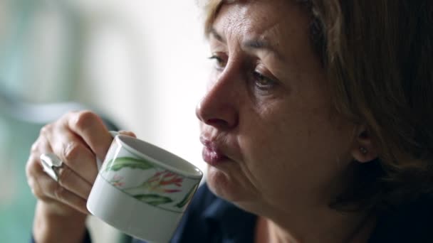 随便的女人在早餐桌上喝了一小口咖啡 在热咖啡上吹着 — 图库视频影像