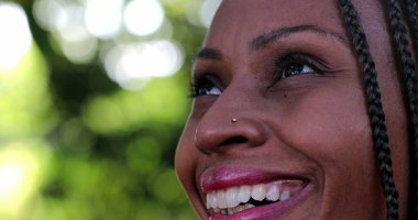 Mutlu kadın gülümseyen gözlerle gökyüzüne bakıyor. Afrika etnik kökeni