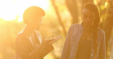 Sokağın ortasında gün ışığıyla konuşan iki kadın.