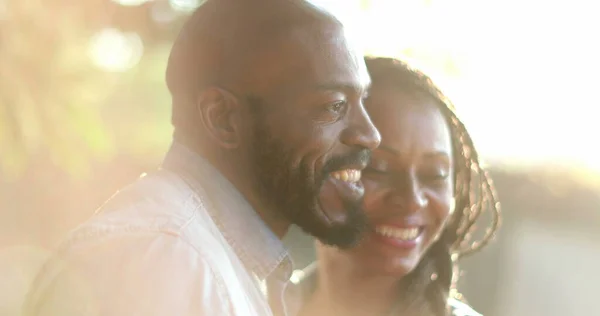 Candid African couple together outside at park. Woman kissing man in cheek outside