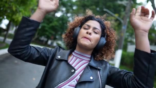 ヘッドフォンを身に着けている通りの外の音楽に踊る無料の黒人女性 — ストック動画