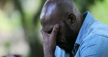 Hüsrana uğramış siyah adam cep telefonundan kötü haberler alıyor.