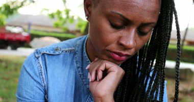 Düşünceli siyah kadın aşağı bakıyor. Endişeli.