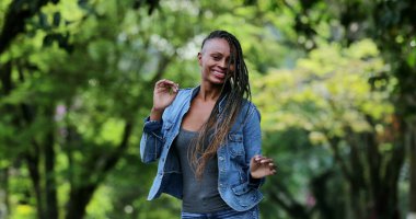 Neşeli bir Afrikalı kadın dışarıda dans ediyor. Başarıyı kutlayan kişi dans eder