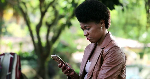 Sad black woman looking at cellphone device