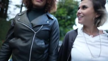 Dışarıda el ele tutuşan iki mutlu kız arkadaş.