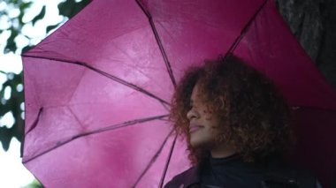 Dışarıda pembe şemsiyeli bir kadın, yağmurlu bir günde Brezilyalı bir kız.