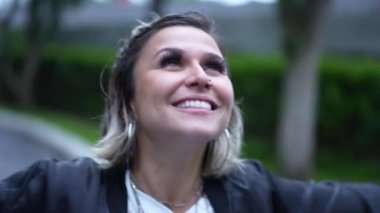 Genç bir kadın yağmur yağarken gökyüzüne bakıp gülümsüyor.