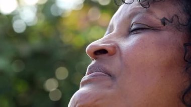 Meditasyonda gözlerini kapatan Brezilyalı bir kadın. Dalgın Afrikalı insan gözlerini gökyüzüne açıyor.