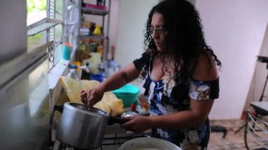 Gündelik İspanyol kadın evde yemek pişiriyor, Güney Amerikalı kadın esrar karıştırıyor.