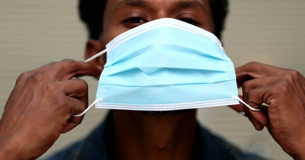 African man wearing covid-19 face mask. Person putting surgical mask