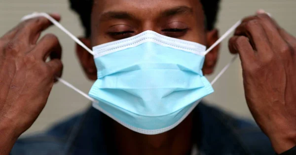 African man removing face mask feeling relief. End of pandemic concept