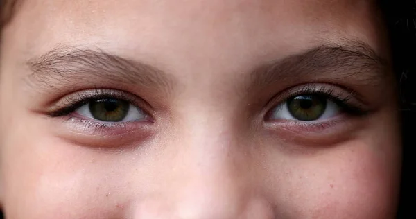 Child closing and opening eyes and smiling, macro green eyes close-up