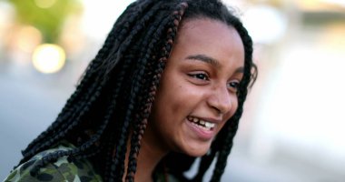 Siyah reşit olmayan kız gülüyor ve gülümsüyor. Gerçek hayatta gül ve gülümse.