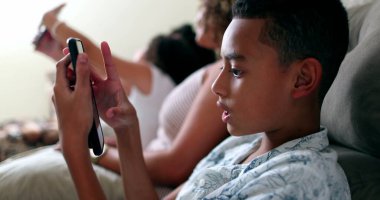 İspanyol genç çocuk cep telefonu kullanıyor. Akıllı telefon aygıtında gizli çocuk oyunu oynuyor