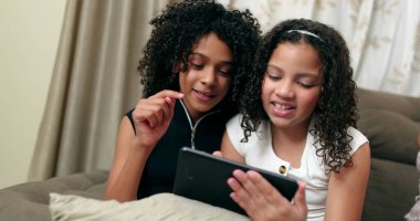 Evde akıllı telefon kullanan iki küçük kız. Genç arkadaşlar akıllı telefon ekranını paylaşıyor