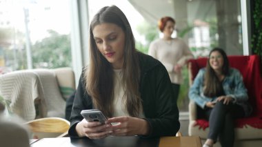 Kahve dükkanında telefon kullanan genç bir kadın. Kafe restoranındaki akıllı telefondan mesaj okuyan kız