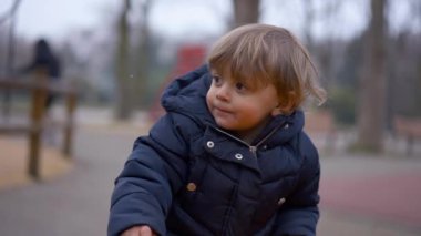 Düşünceli küçük bebek çocuk, çocuk parkında ağır çekimde.