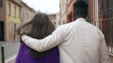 Şehir caddesinde birlikte yürüyen ırklar arası genç bir çift. Siyah adam kız arkadaşına sarılıyor.