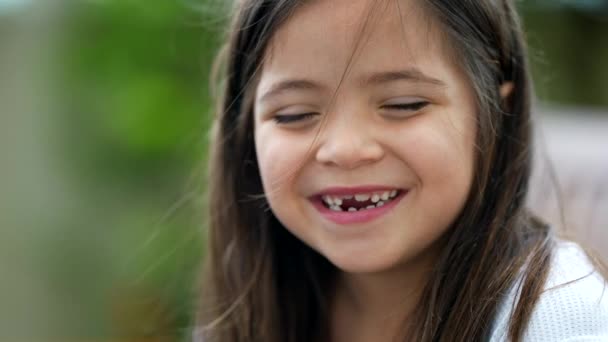 一个快乐的小女孩与失踪的牙齿亲密的脸的肖像 一个带着无牙门牙微笑的快乐的女孩 — 图库视频影像