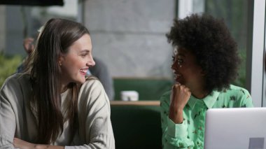 Kafede oturmuş gülen ve gülümseyen genç bir arkadaş grubu. Gerçek hayatta kadınlar kafe 'de güler ve gülümser.