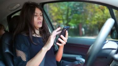 Direksiyonda trafikte cep telefonunu kontrol eden bir kadın. Modern telefondan haritaya bakan kişi. Araba kullanırken tehlikeli davranışlar. Sürücü trafikte sıkıştı.
