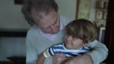 Torun büyükbabanın kucağında oturuyor. Otantik gerçek hayat aile nesli ilişkisi. Büyükbaba ve torun arasındaki sevgi ve sevgi
