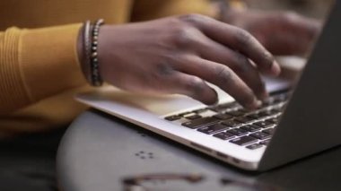 Yakın plan Afrikalı erkek elleri dizüstü bilgisayarda klavye yazıyor.